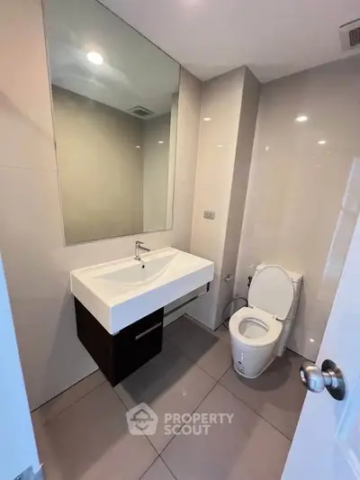 Modern bathroom with sleek fixtures and large mirror in a contemporary apartment.