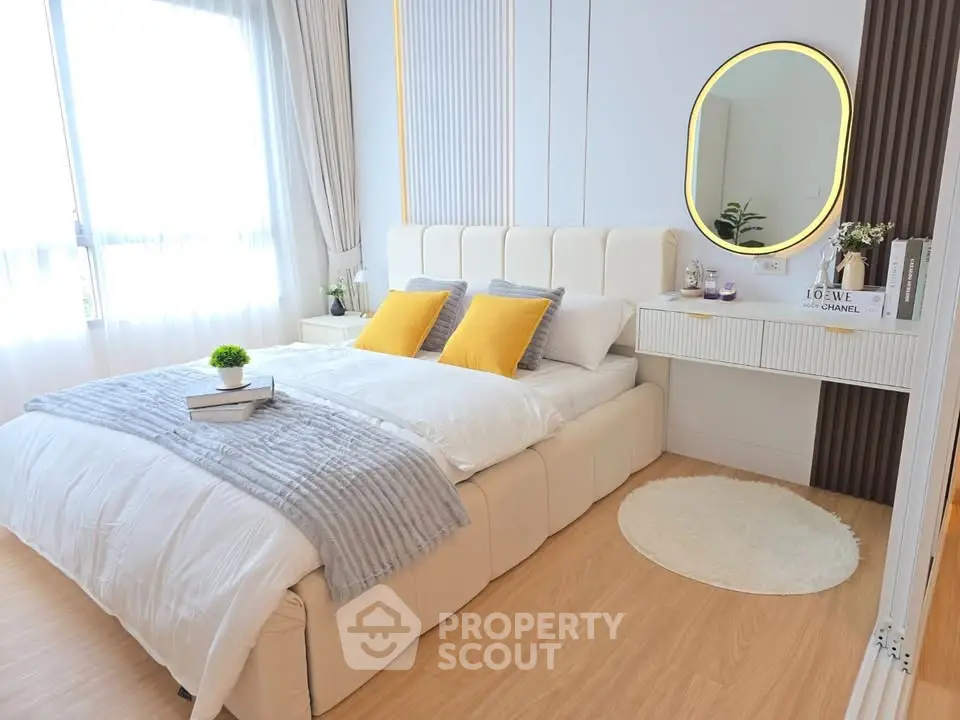 Elegant bedroom with modern decor, featuring a plush bed, stylish mirror, and natural light from large windows.