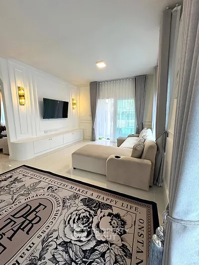 Elegant living room with modern decor, large sofa, and wall-mounted TV, perfect for relaxation and entertainment.