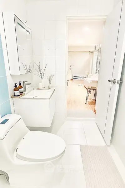 Modern bathroom with sleek fixtures and open door view to bright living area.