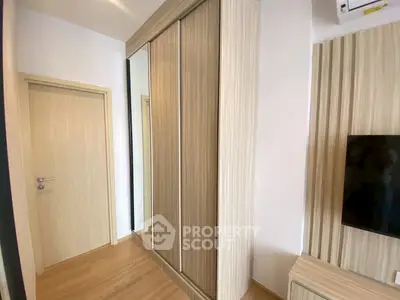 Modern bedroom with sleek wooden wardrobe and wall-mounted TV, showcasing minimalist design.