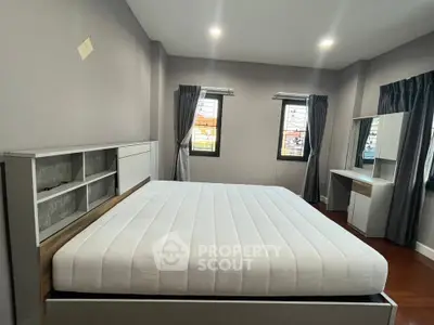 Spacious bedroom with modern furnishings and large windows for natural light.