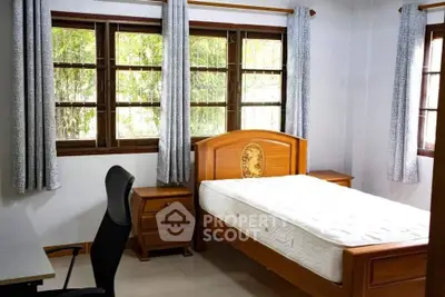Cozy bedroom with wooden bed frame, large windows, and natural light.