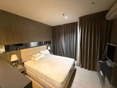 Modern bedroom with cozy lighting and stylish decor, featuring a comfortable bed and elegant curtains.