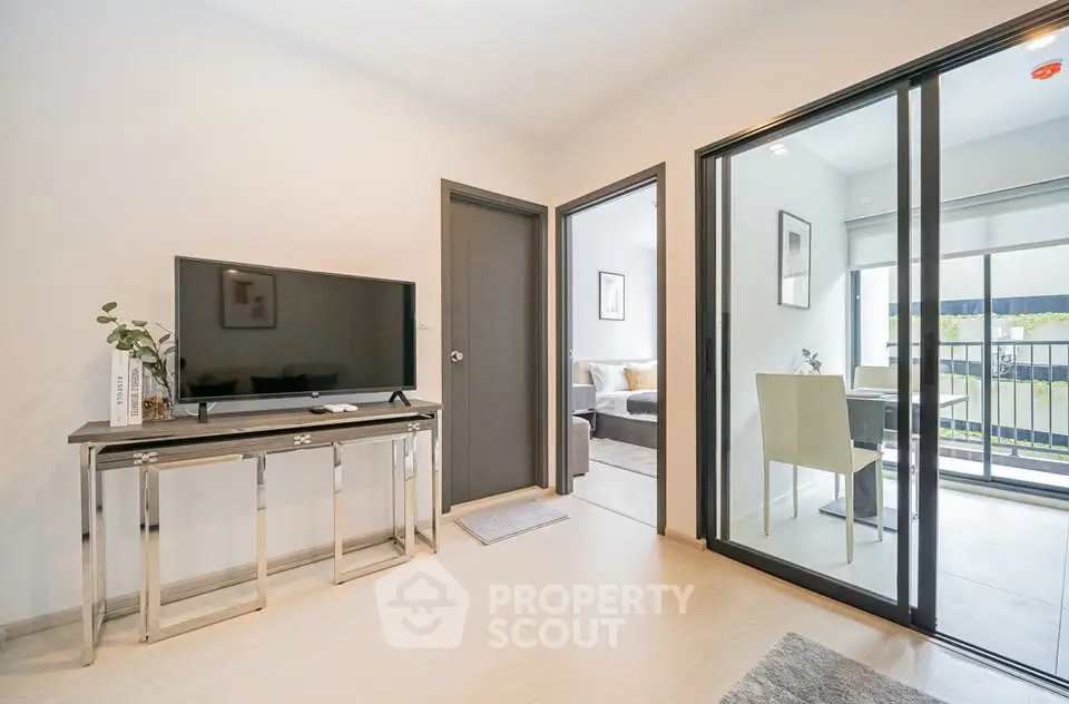 Modern living room with sleek TV setup and sliding glass doors to balcony