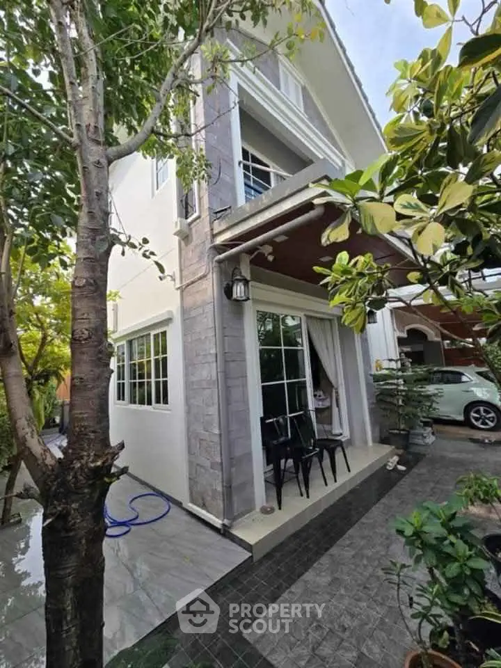 Charming two-story house with lush garden and inviting patio area.