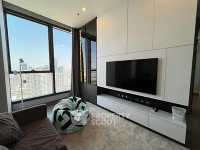 Modern living room with large windows and city view, featuring sleek entertainment center and cozy seating.
