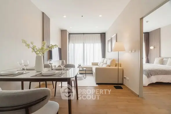 Modern open-plan living room with dining area and cozy bedroom in elegant apartment.