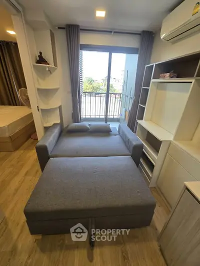 Modern studio apartment with convertible sofa bed and balcony view, perfect for urban living.