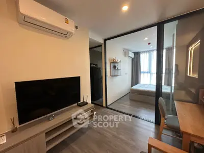 Modern studio apartment with open layout, featuring a cozy living area and bedroom separated by glass partition.