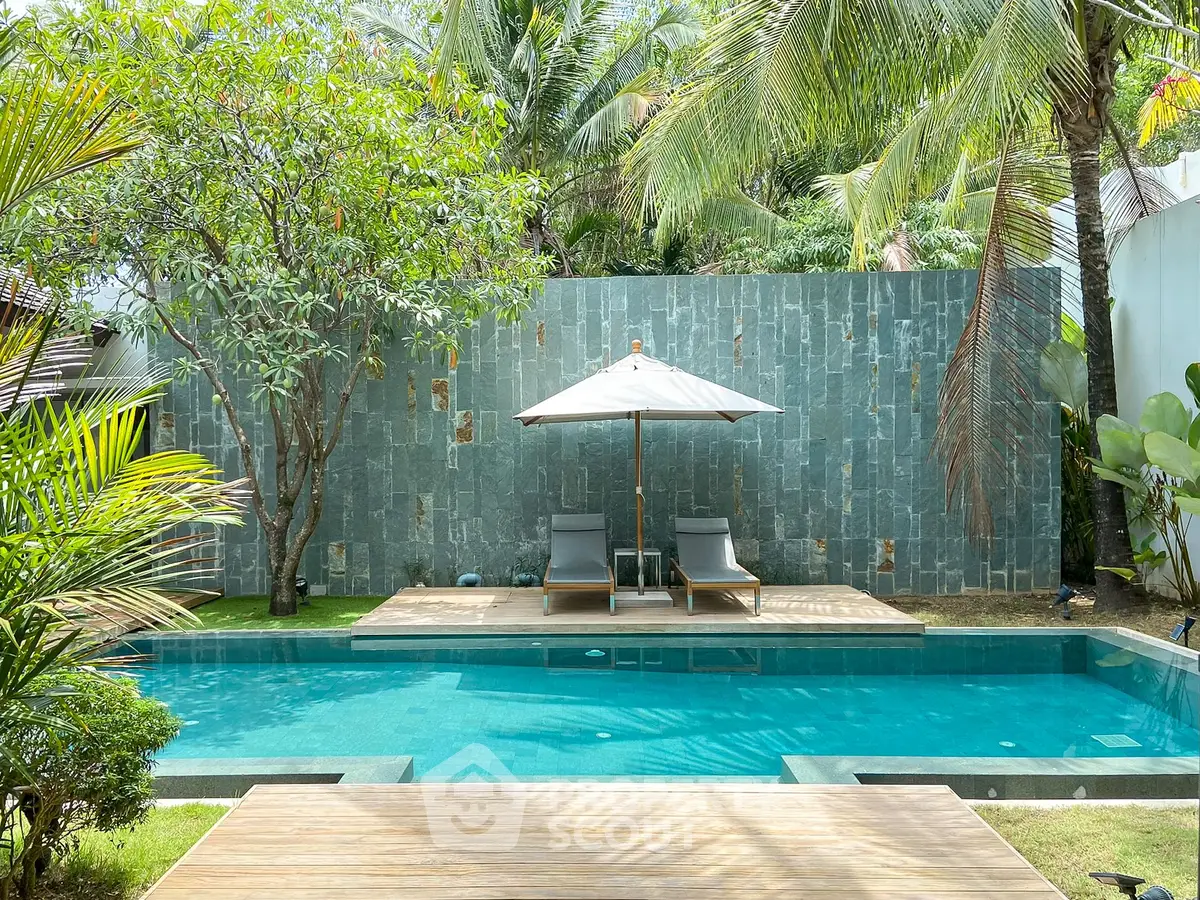 Luxurious private pool with sun loungers and tropical garden setting, perfect for relaxation and leisure.