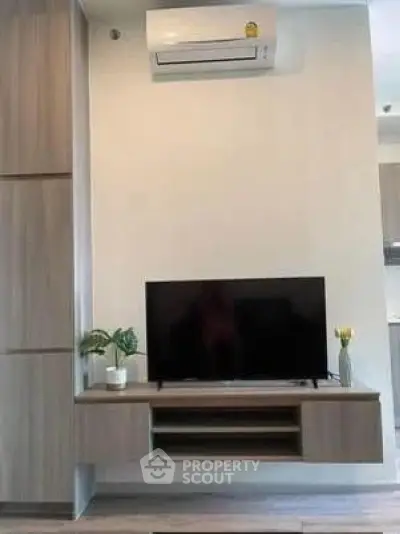 Modern living room with sleek TV setup and air conditioning unit.