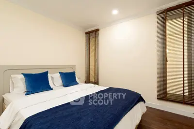 Modern bedroom with cozy bed and stylish blue accents in a well-lit space.