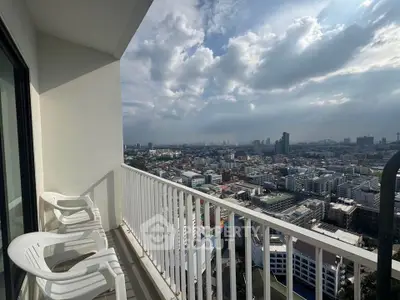 Stunning cityscape view from high-rise balcony with seating, perfect for relaxation.