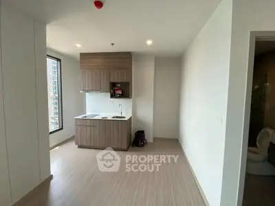 Modern minimalist kitchen with wooden cabinets and large window in a bright apartment.