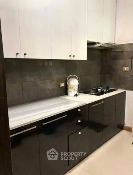 Modern kitchen with sleek black and white cabinetry and gas stove.
