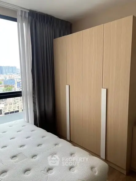 Modern bedroom with large window and sleek wardrobe design.