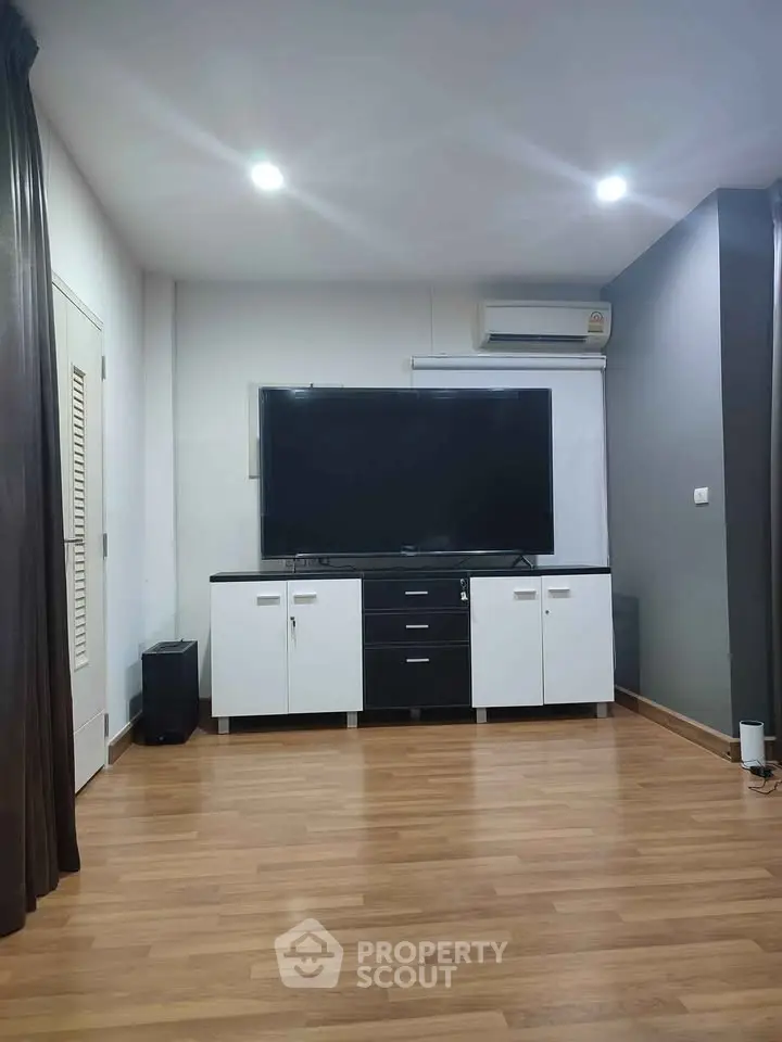 Modern living room with sleek TV setup and wooden flooring, perfect for entertainment and relaxation.