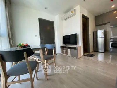 Modern living room with dining area and kitchen, featuring sleek furniture and appliances.