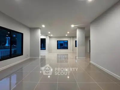 Spacious modern living room with large windows and glossy tiled floors, perfect for natural light and open living.