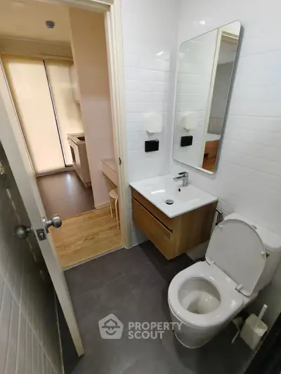 Modern bathroom with sleek fixtures and adjacent view of kitchen area.