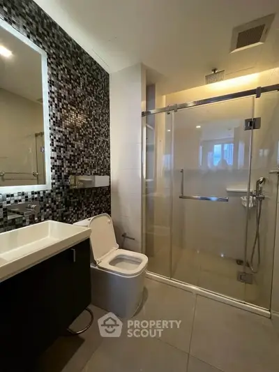 Modern bathroom with glass shower and stylish tile wall in luxury apartment.