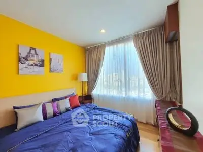 Vibrant bedroom with yellow accent wall and large window, featuring modern decor and cozy bedding.