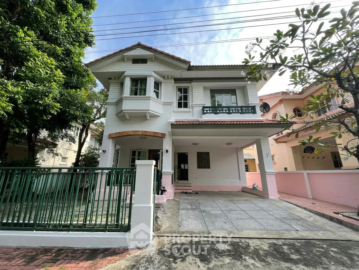 Charming two-story house with spacious driveway and lush greenery in a serene neighborhood.