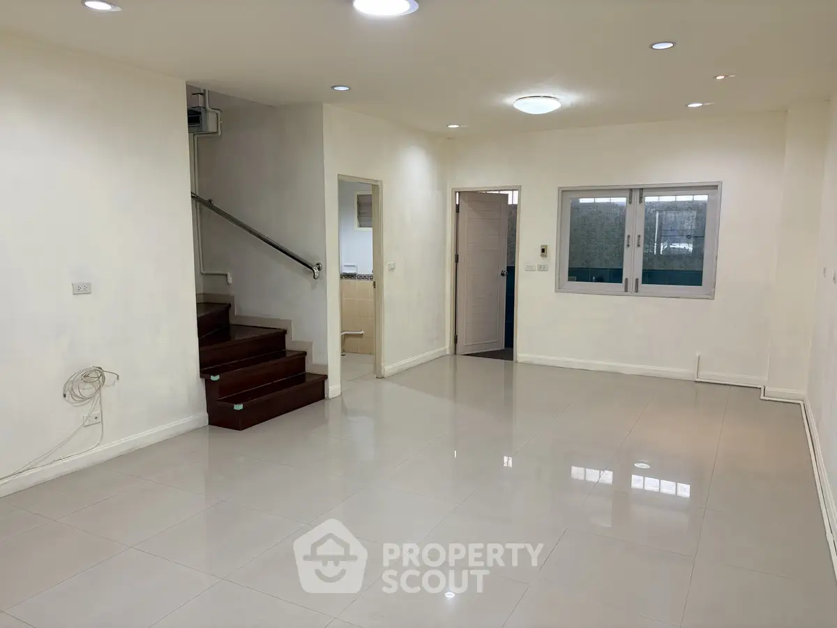 Spacious modern living room with staircase and tiled flooring in a contemporary home.