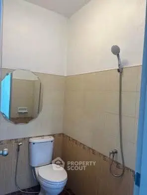 Compact bathroom with shower and toilet, featuring neutral tile design.