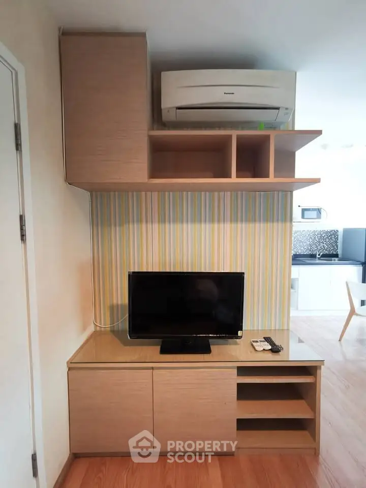 Modern living room with built-in TV cabinet and air conditioning unit, featuring stylish wood finishes.