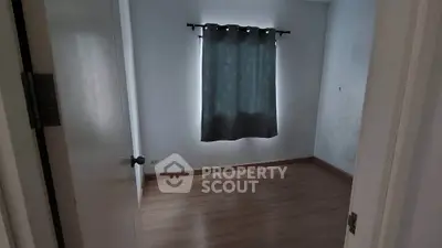 Spacious empty room with wooden flooring and a window with curtains, ideal for customization.