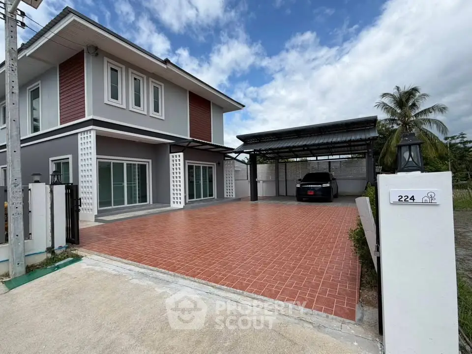 Modern two-story house with spacious driveway and carport, featuring contemporary design and lush surroundings.