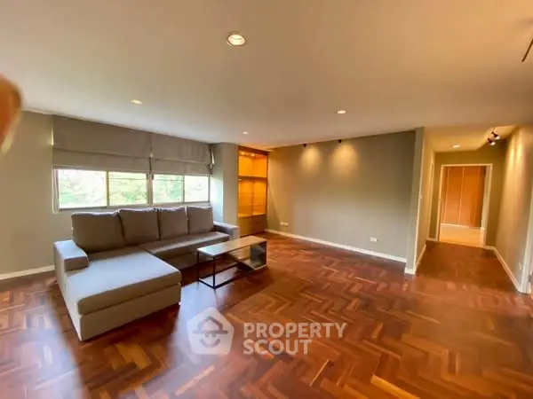 Spacious living room with elegant wood flooring and modern sofa, ideal for relaxation.