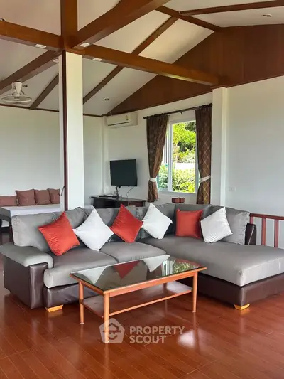 Spacious living room with modern sofa and wooden accents, offering a cozy and inviting atmosphere.