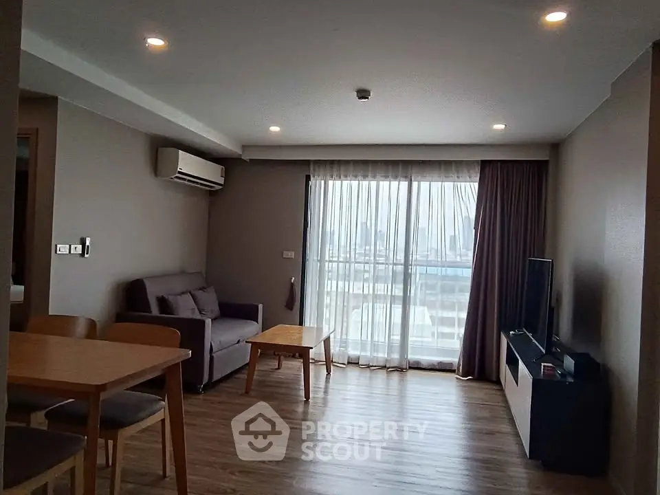 Modern living room with city view, featuring cozy seating and sleek decor.