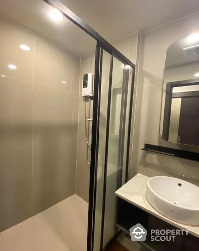 Modern bathroom with sleek glass shower enclosure, stylish basin, and well-lit vanity mirror, perfect for contemporary living.