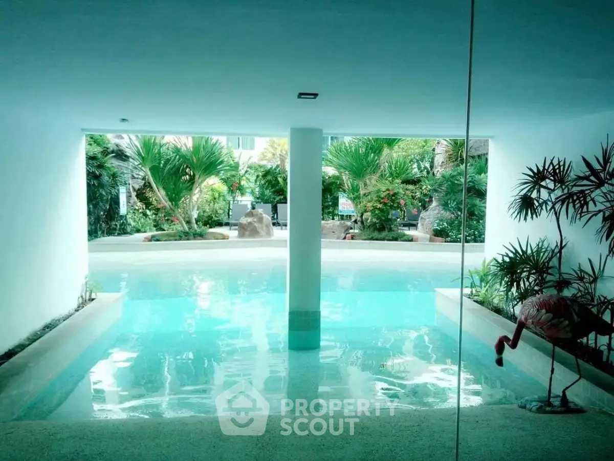 Luxurious indoor pool with tropical garden view, perfect for relaxation and leisure.