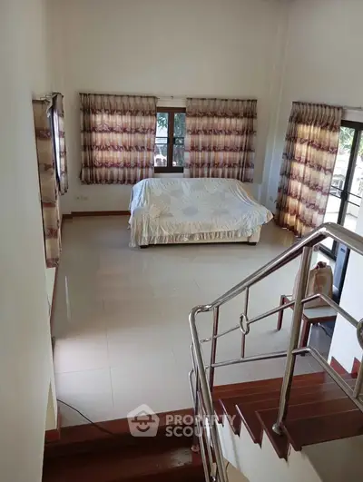 Spacious living room with large windows and modern staircase in a bright, airy home.