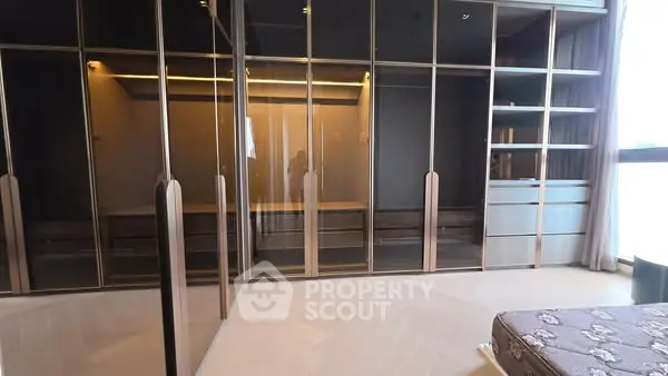 Spacious bedroom with elegant glass wardrobes and ample natural light.