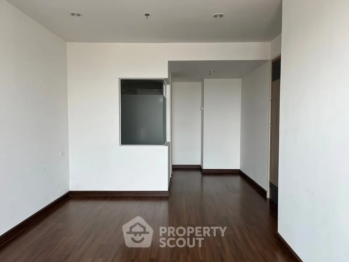 Spacious empty room with wooden flooring and white walls, ideal for customization.