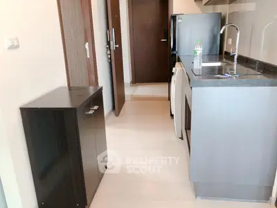 Modern kitchen with sleek cabinetry and compact design, featuring a fridge and sink area.