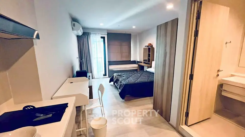 Modern studio apartment with open layout, featuring a cozy bed, study desk, and kitchenette.