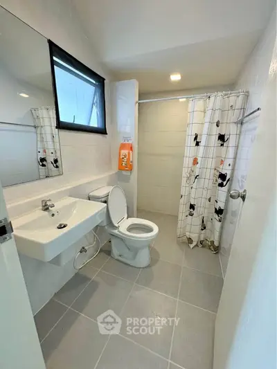 Modern bathroom with sleek fixtures and stylish shower curtain in a bright, tiled space.