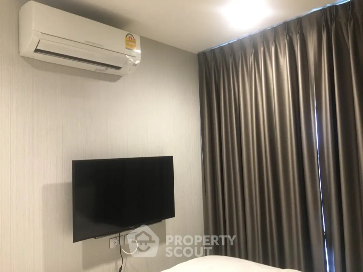 Modern bedroom with wall-mounted TV and air conditioning unit