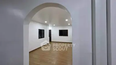 Spacious modern interior with archway and wooden flooring, ideal for versatile living space.