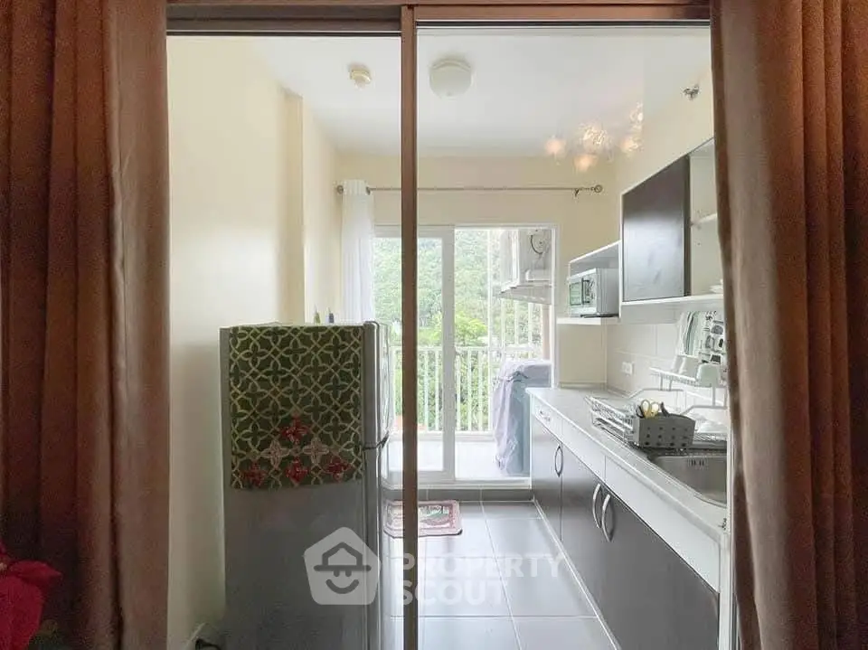 Modern kitchen with balcony view, sleek cabinets, and natural light.
