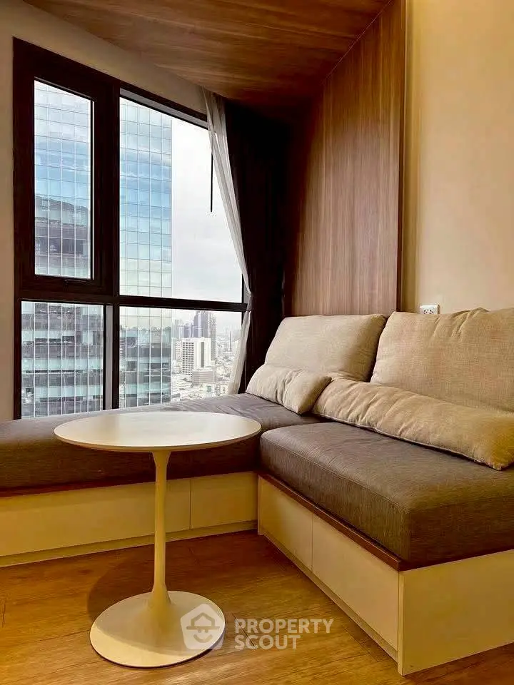 Cozy corner unit with modern sofa and city view through large windows.