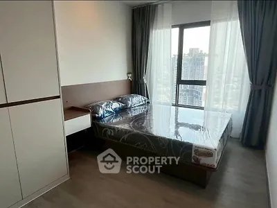 Modern bedroom with large window offering city view, featuring sleek furniture and stylish decor.