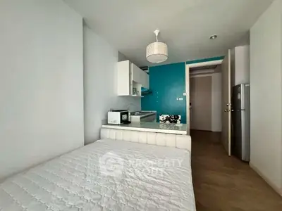 Modern studio apartment with compact kitchen and cozy sleeping area, ideal for urban living.